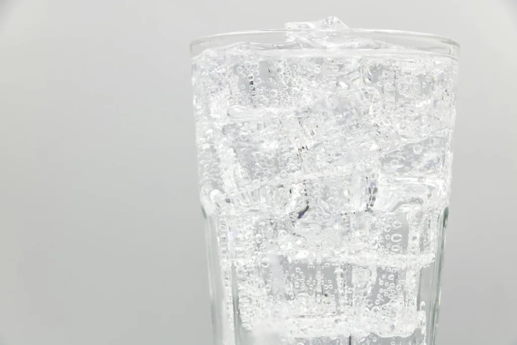 Close-up of a glass filled with sparkling water and ice cubes, ideal for refreshing summer drinks.