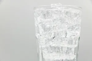 Close-up of a glass filled with sparkling water and ice cubes, ideal for refreshing summer drinks.